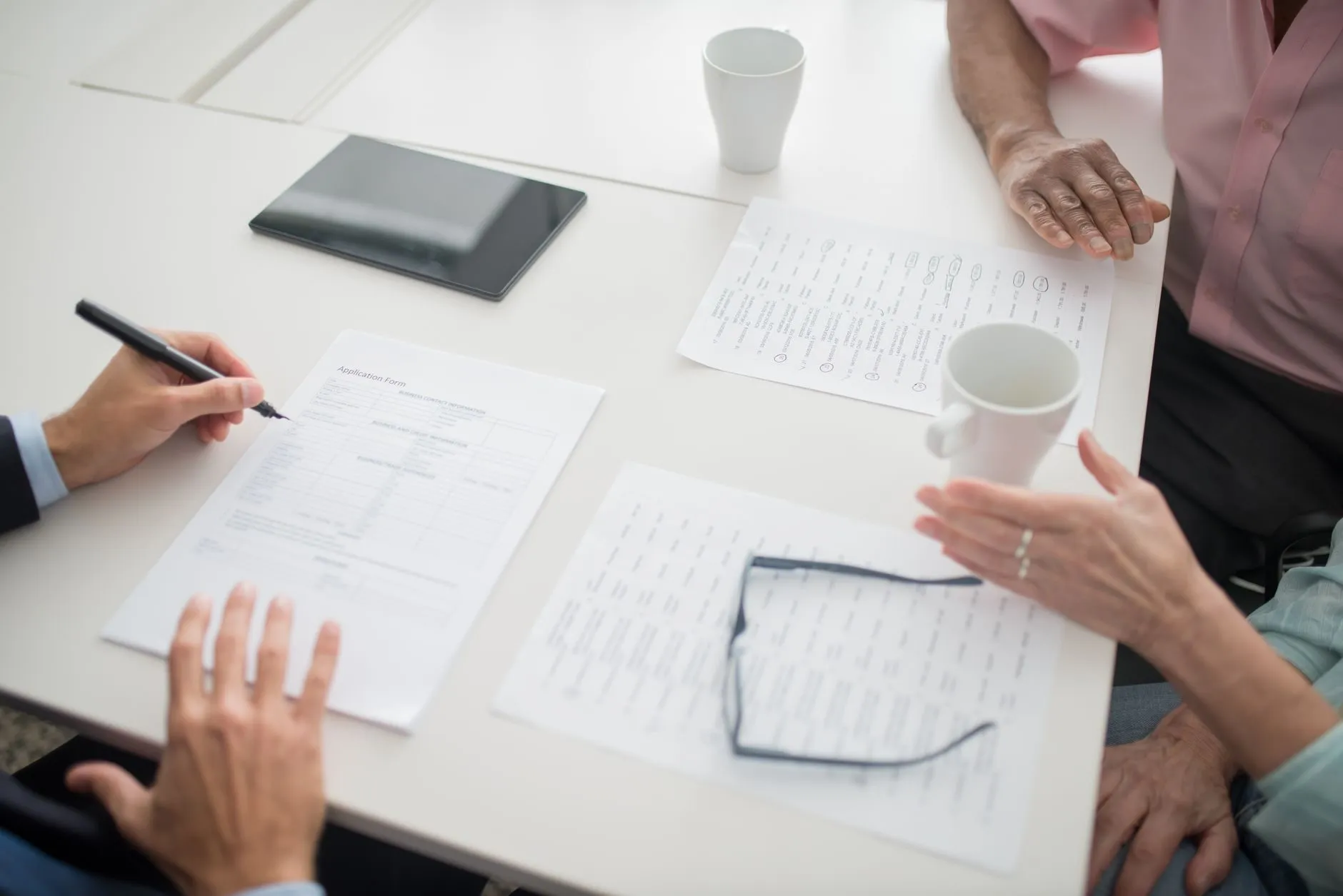 Hands going through an application form across a white table